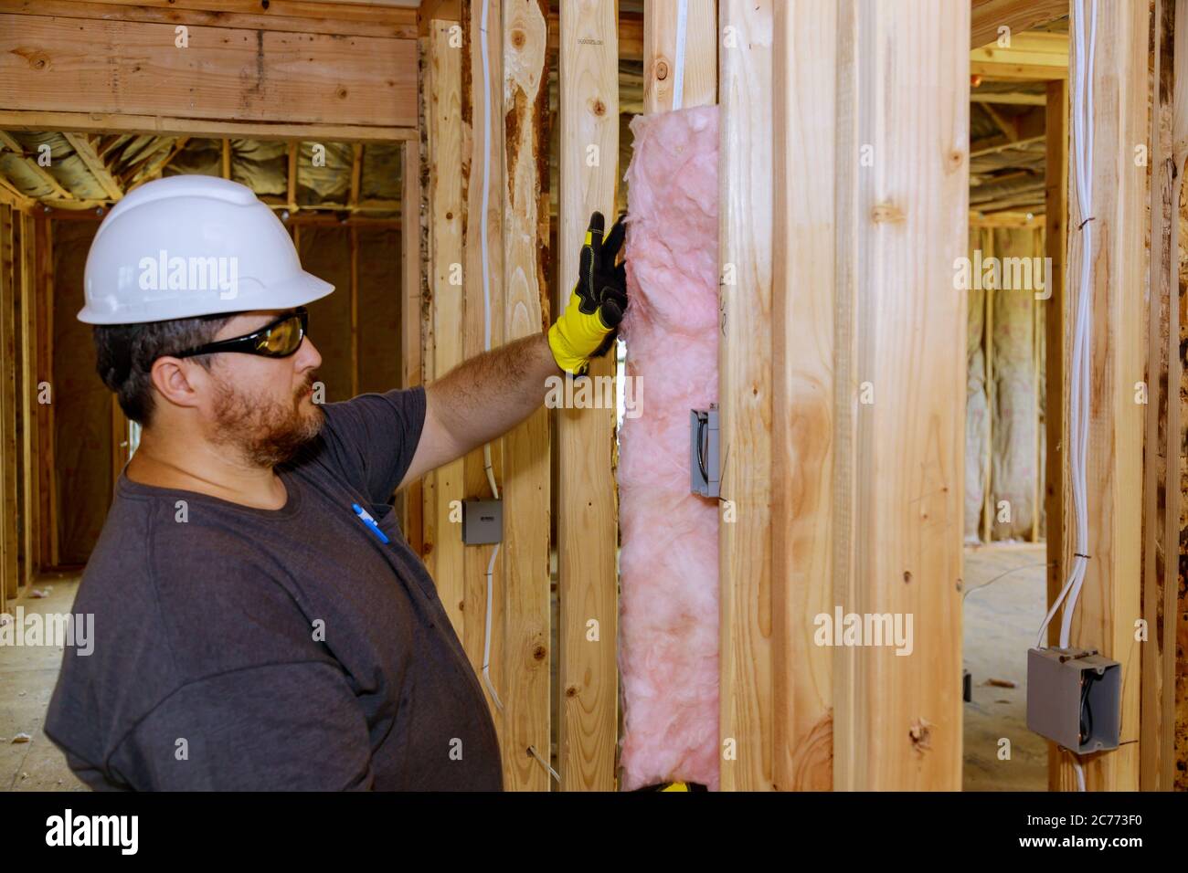 Construction worker installing thermal insulation layer under the wall