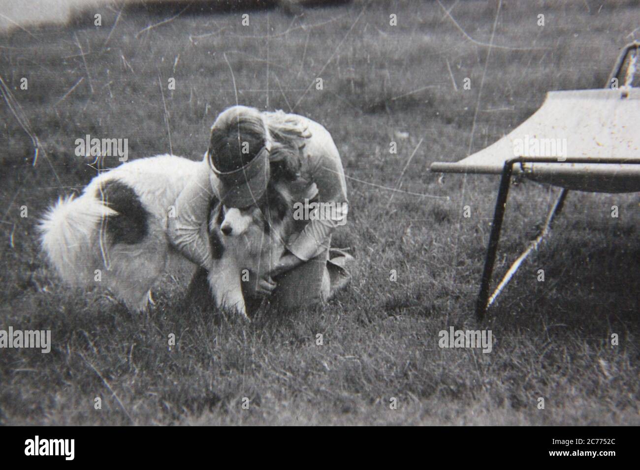 Fine 70s vintage black and white lifestyle photography of a teenage girl playing with her dog outside. Stock Photo