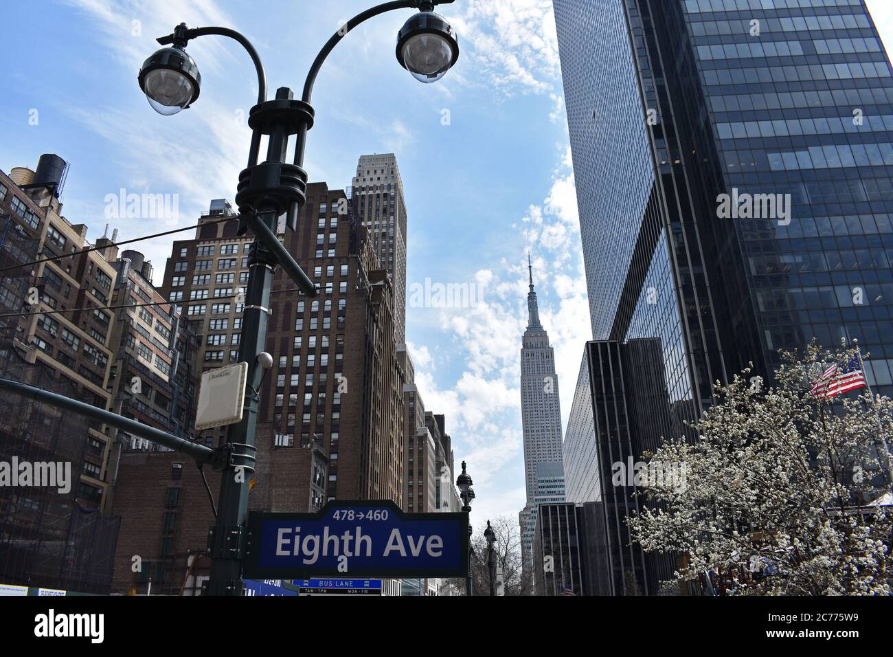 A view of the Empire State Building from Eighth Avenue. On one side is modern black building and older art deco buildings on the other. Stock Photo