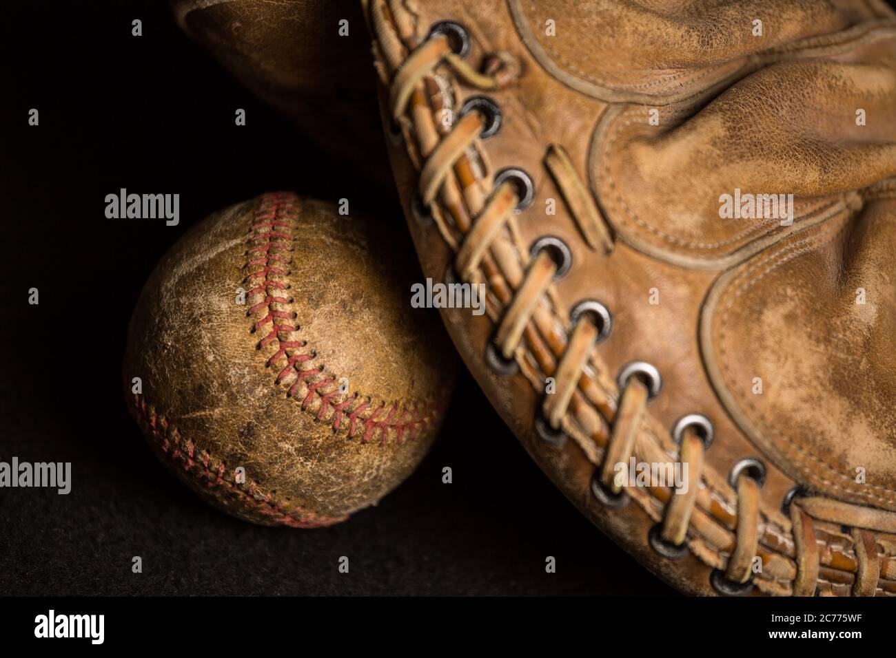 Old style baseball glove near stained and well used ball. Stock Photo