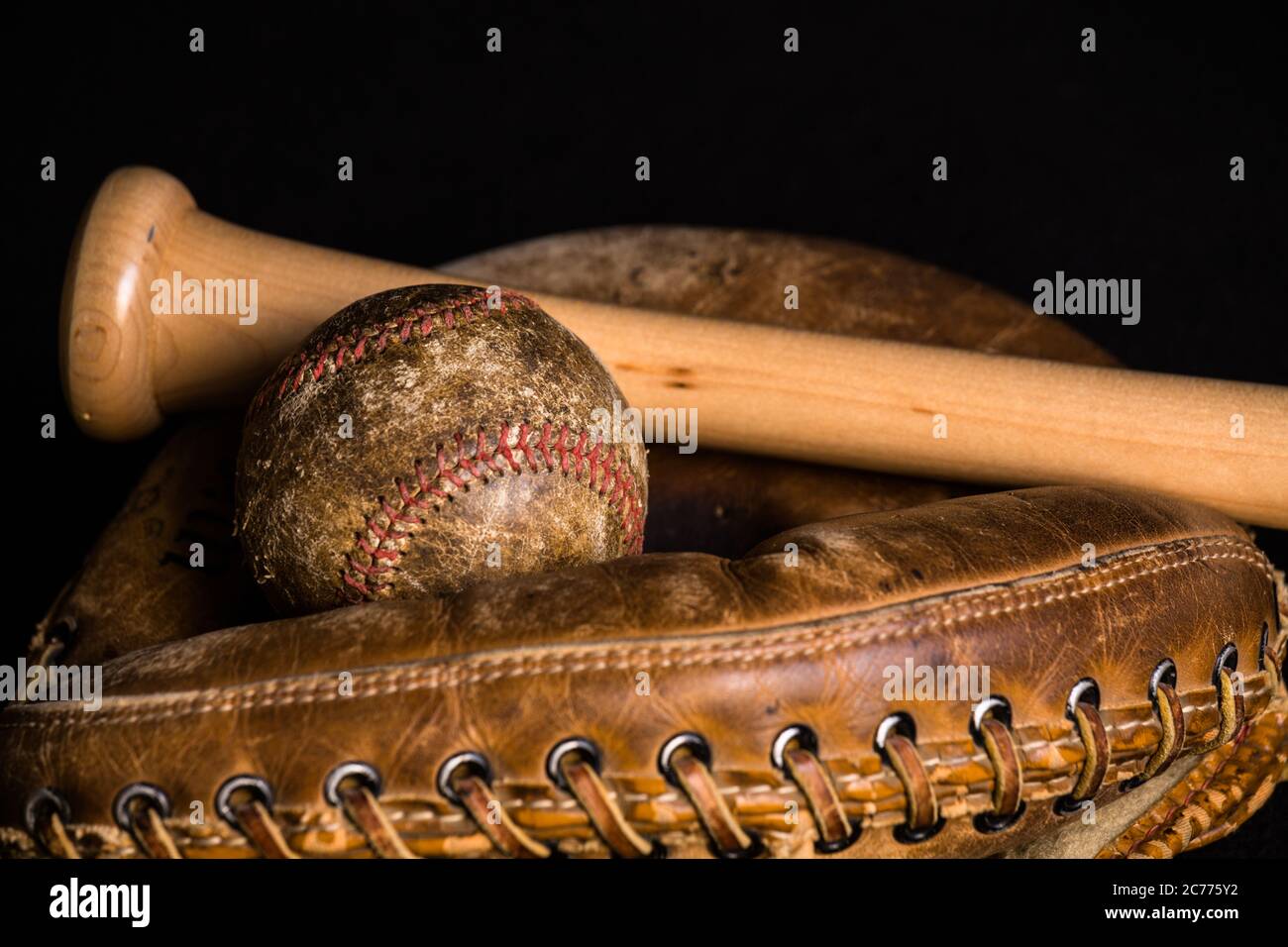 Old baseball, stained and wonrn out, and old style catchers mitt joined by a brand new baseball bat. Stock Photo