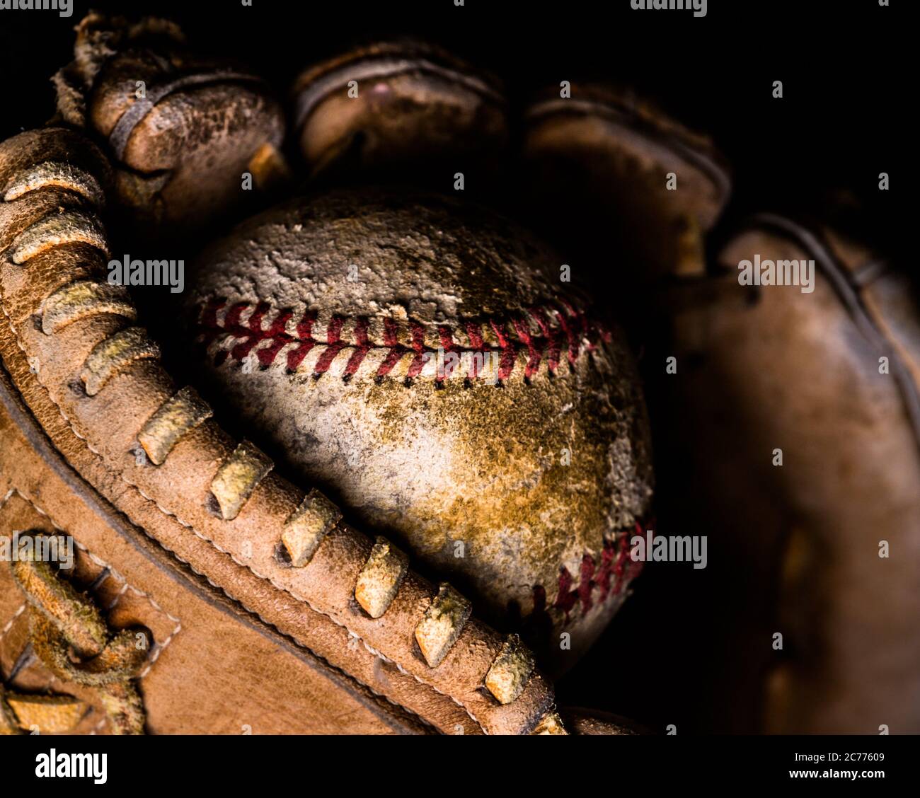 Basball caught just in the end of an old leather glove, lit from the side. Stock Photo