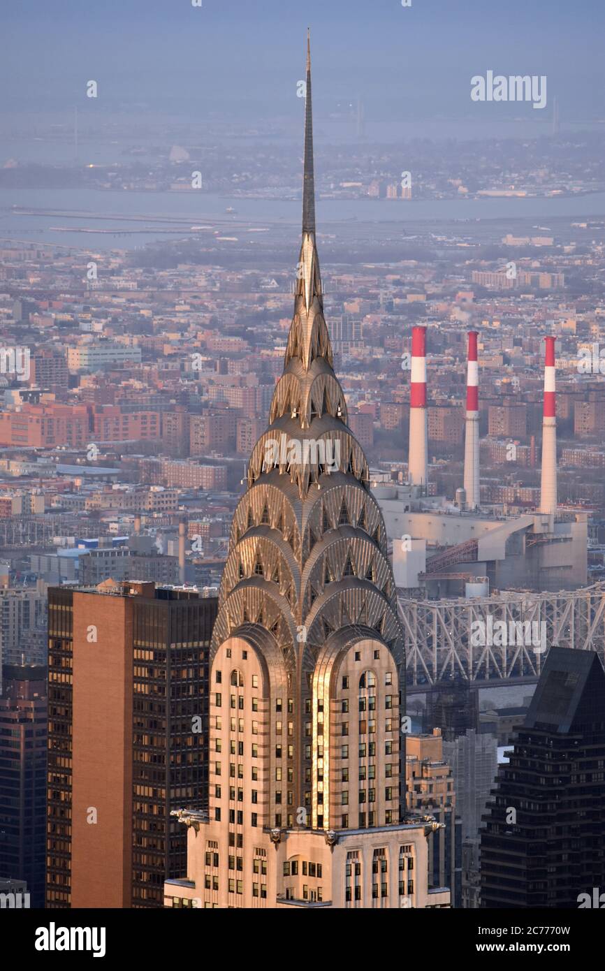 The top of the art deco Chrysler Building glowing at sunset.  Taken from the top of the Empire State Building.  Also in shot is the Queensboro Bridge. Stock Photo