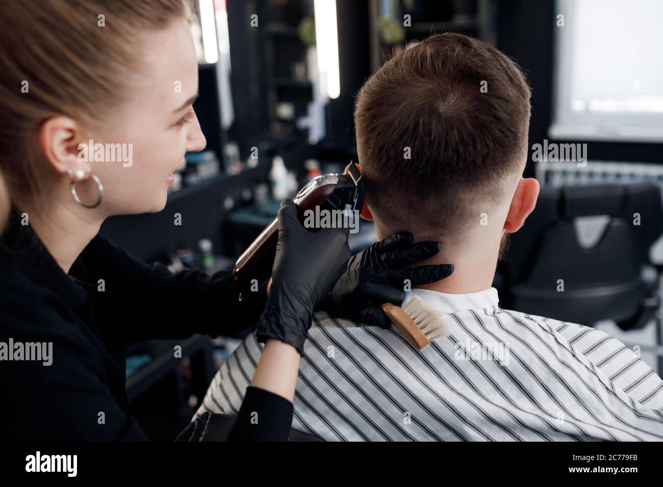 Backside of a man in Barbershop, cutting by barber girl Stock Photo