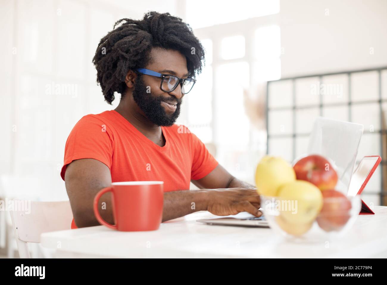 Young black man working at home with laptop and tea cup Stock Photo