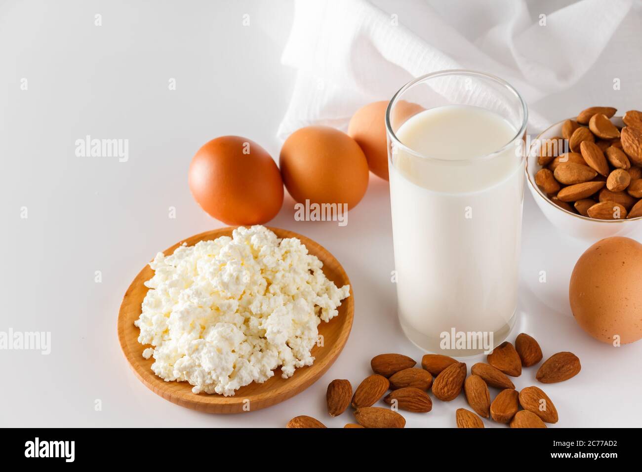 High protein food on a white background - cottage cheese, eggs, nuts. A set of healthy foods for a balanced diet. Stock Photo