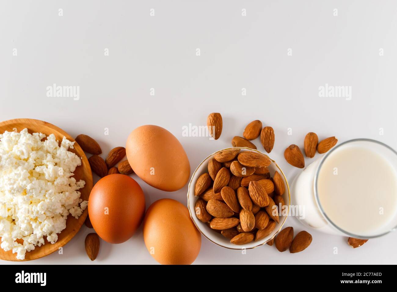 A set of healthy protein foods for a balanced diet. Cottage cheese, eggs and nuts on a white
