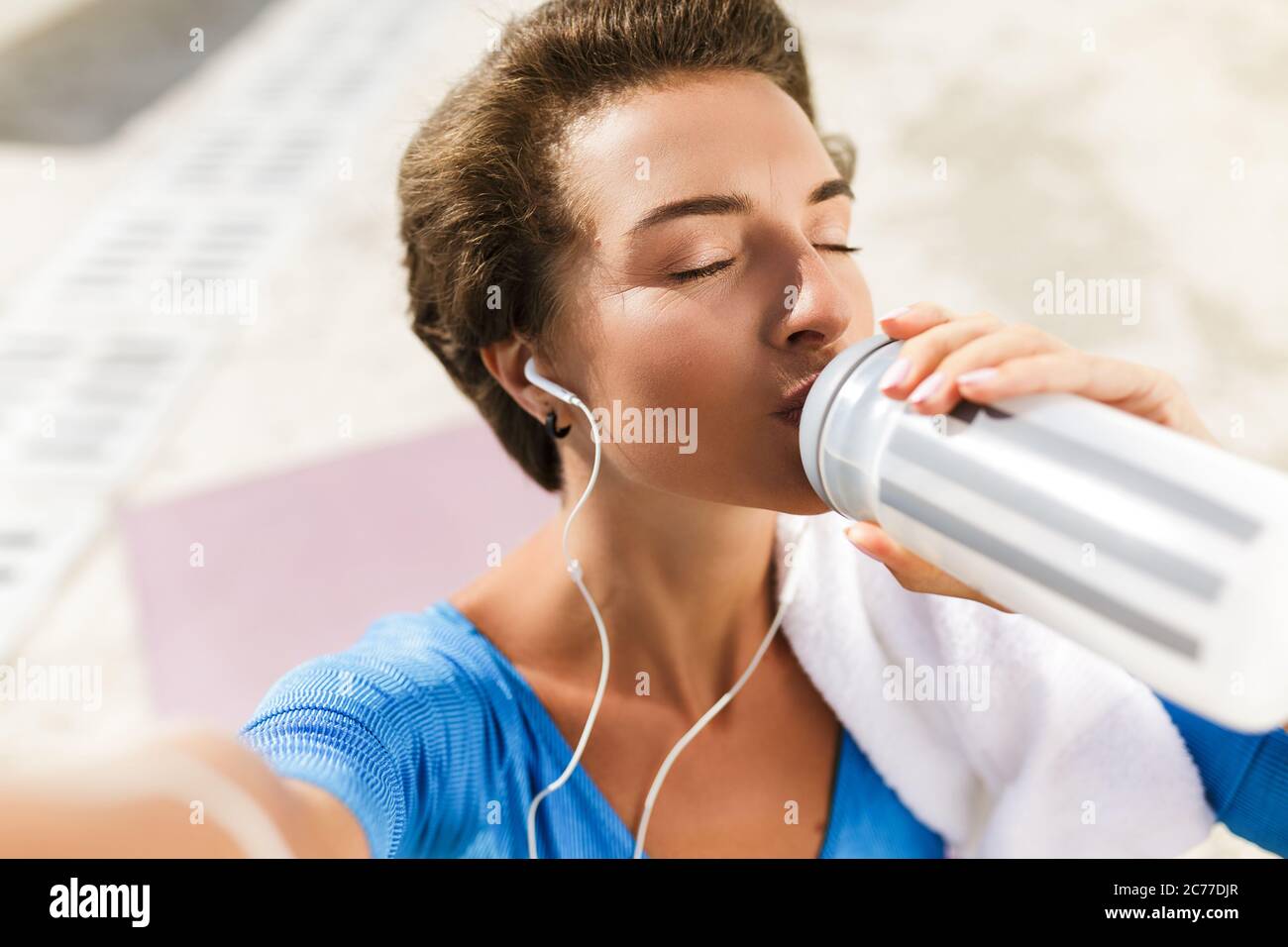 Woman in swimsuit dreamily closed her eyes while drinking water and taking selfie Stock Photo