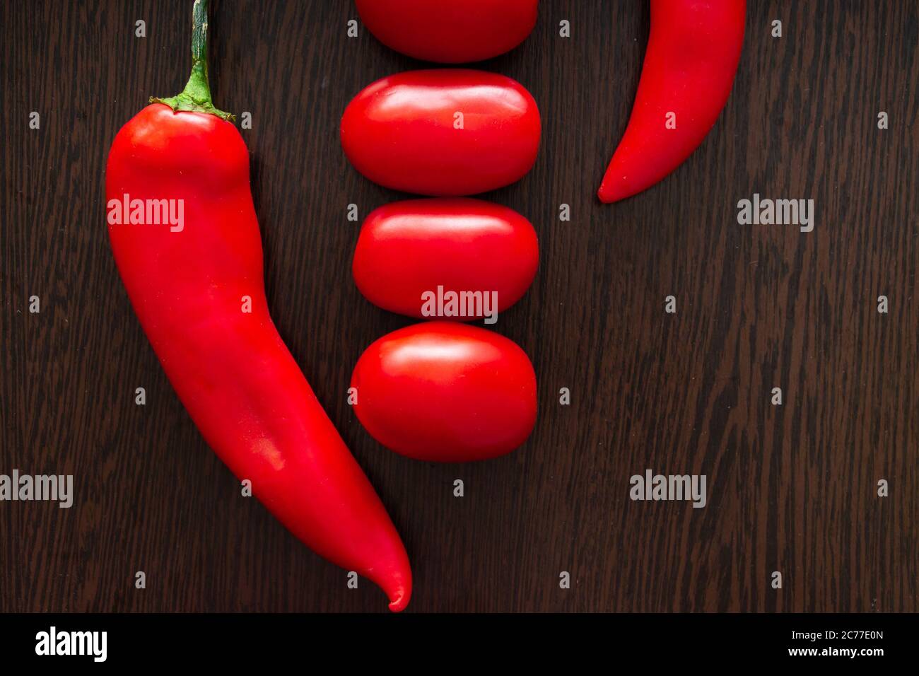 Chili peppers and tomatoes on a dark wooden background Stock Photo - Alamy
