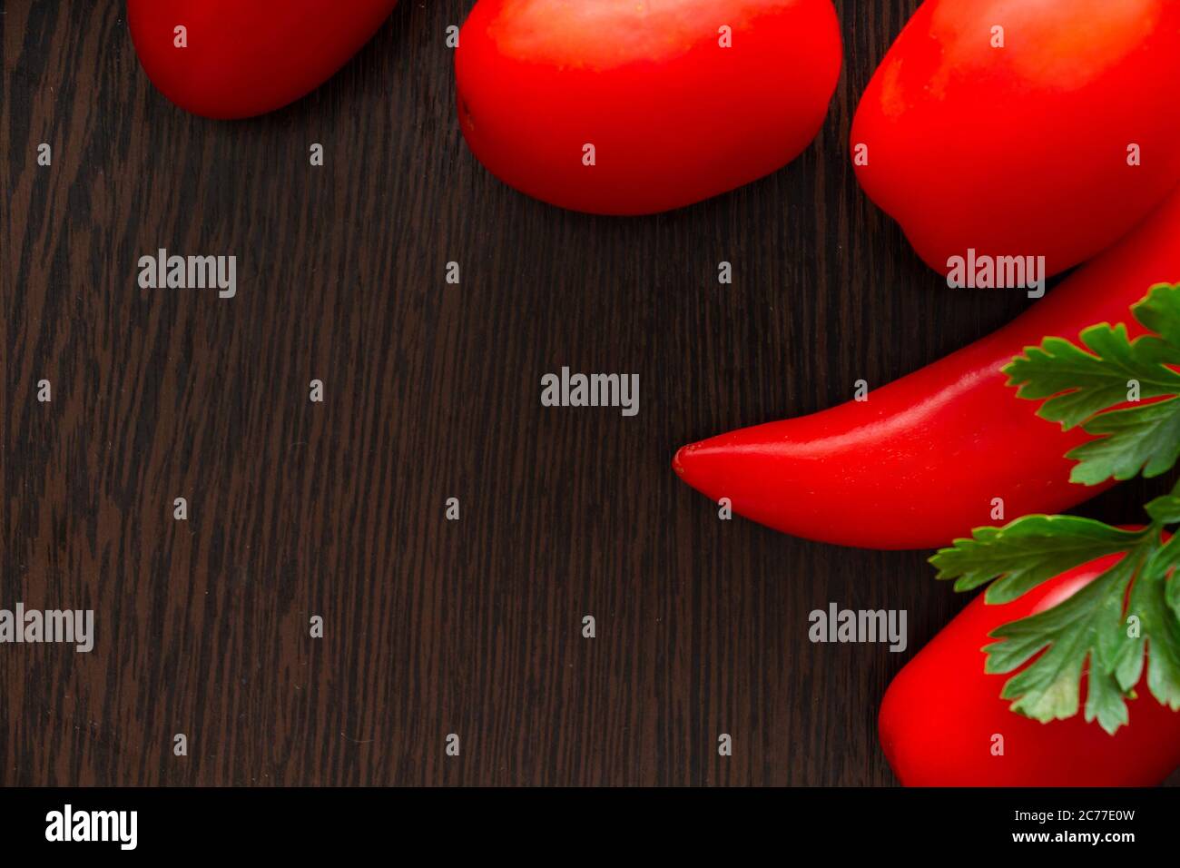 Chili peppers and tomatoes on a dark wooden background Stock Photo - Alamy
