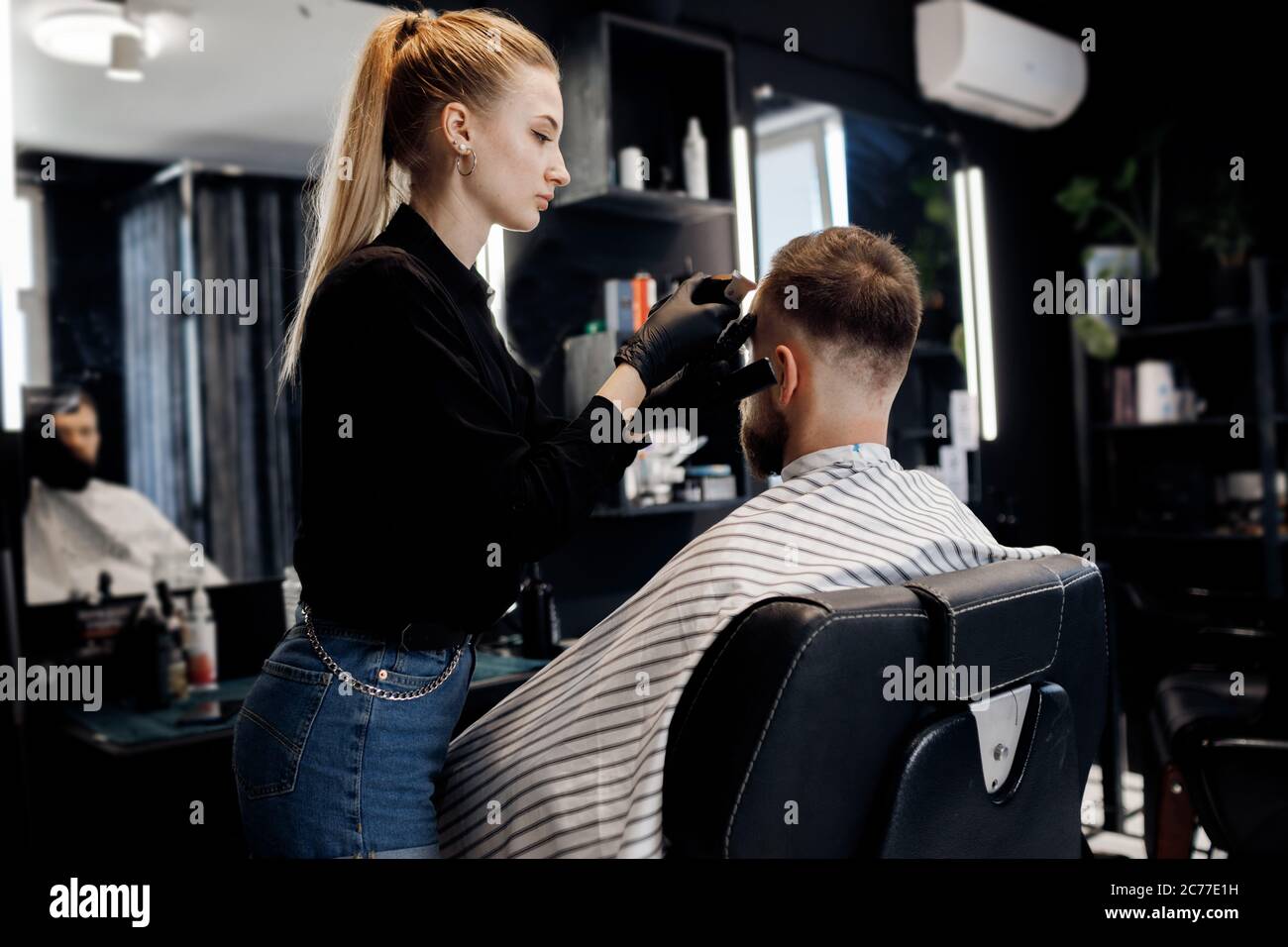 Portrait of a man in Barbershop, shave and cut by barber girl Stock Photo
