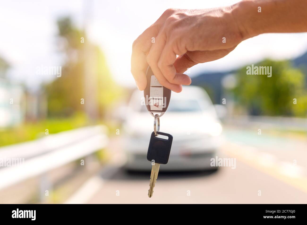 Hand man holding car keys and blur car in background Stock Photo - Alamy