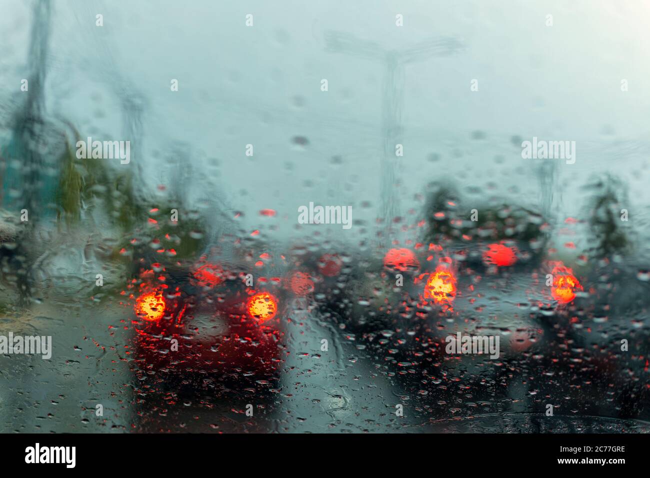 drive a car on the road stop witn trafic light with raindrop over the wind shield. Shot form wind shield Stock Photo