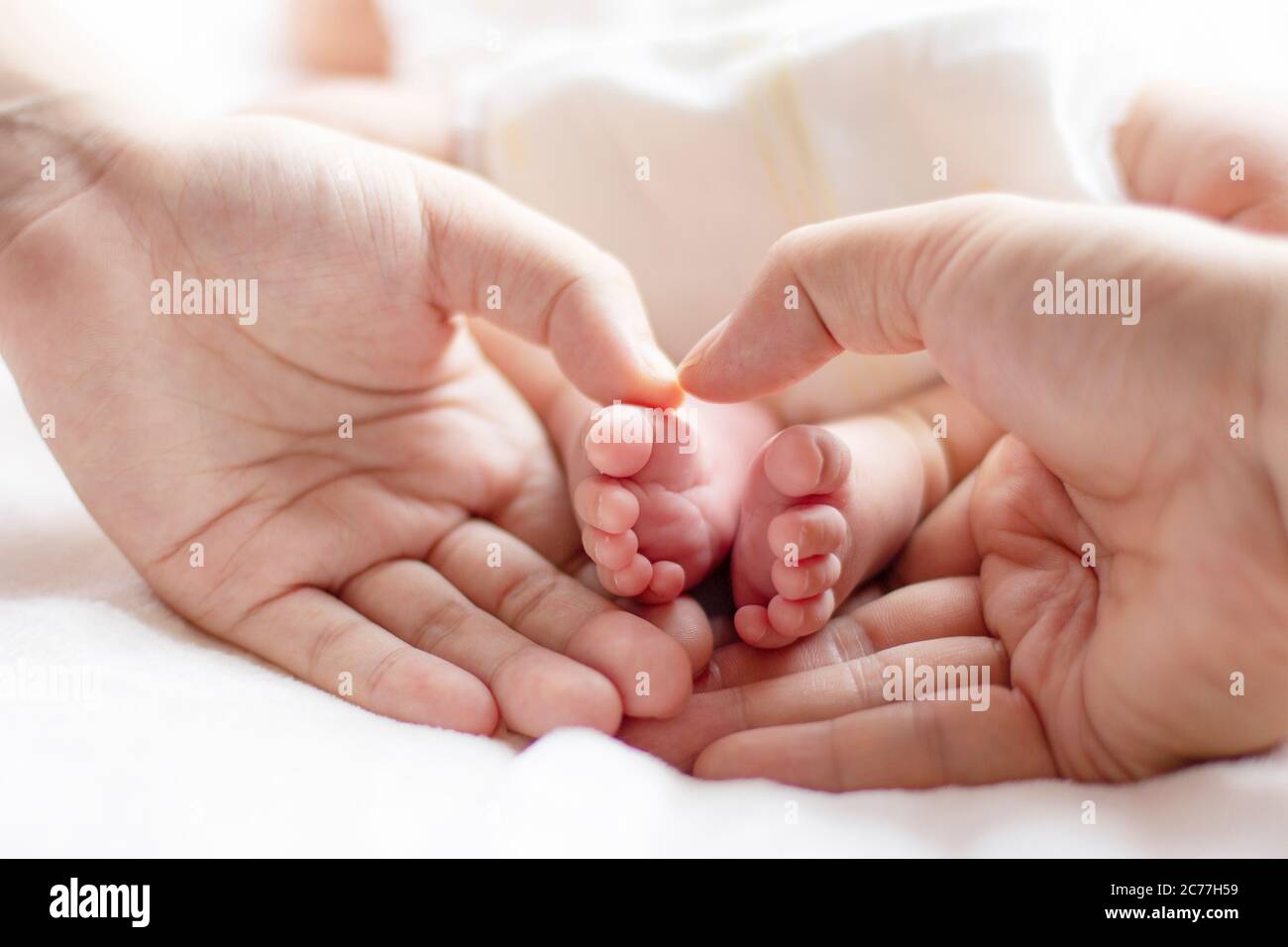 Baby and mother and father holding footers, cropped, close-up Stock Photo