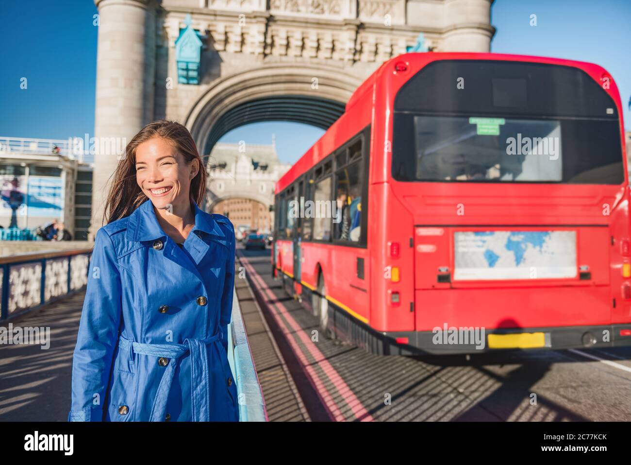 London woman walking commute on Tower Bridge city street using public transport bus commuting in the morning. Happy young Asian british business Stock Photo
