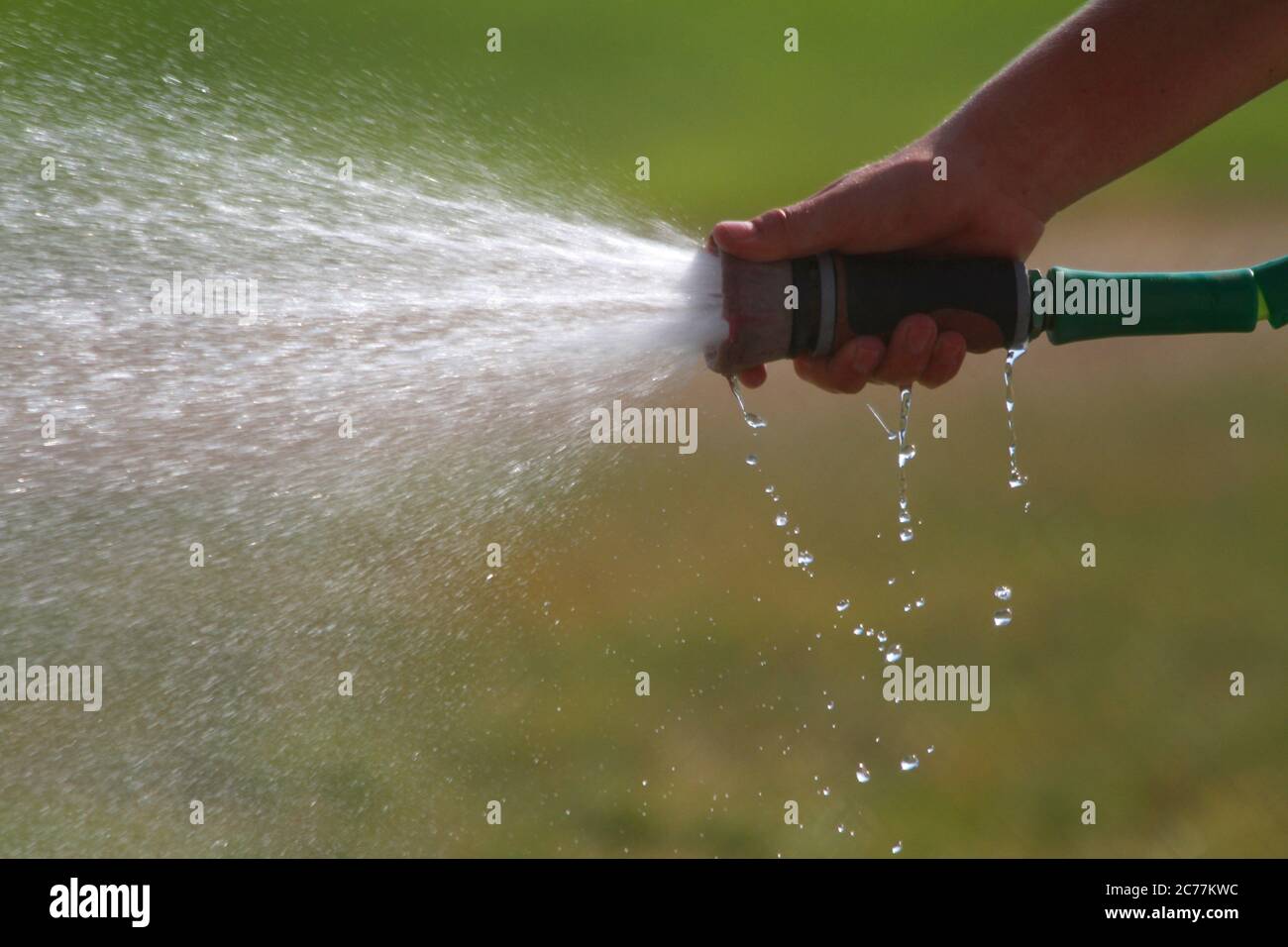 A man sprays water from a hose in a close-up photograph. Stock Photo