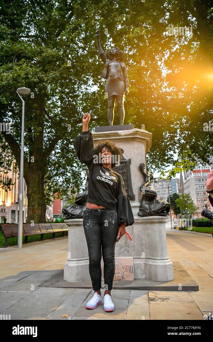 Jen Reid poses in front of her black resin and steel statue titled A Surge of Power (Jen Reid) 2020, by Marc Quinn, where it is installed on the vacant Edward Colston plinth in Bristol city centre. Stock Photo