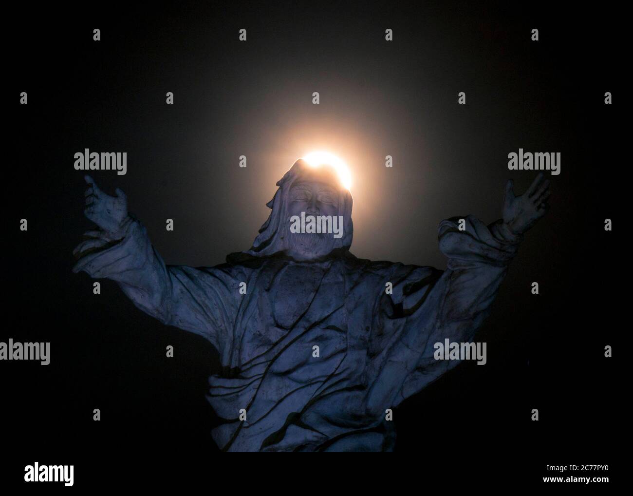 Full moon passing over a statue of Jesus in La Esperanza, Honduras