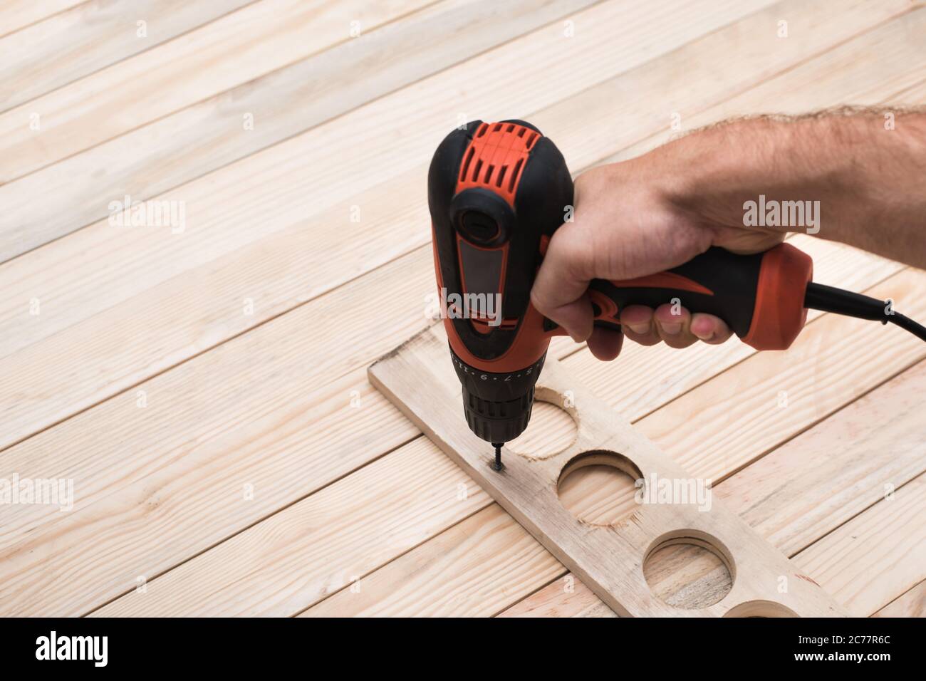 Electric drill screwdriver in male hand. Tightening screw, processing