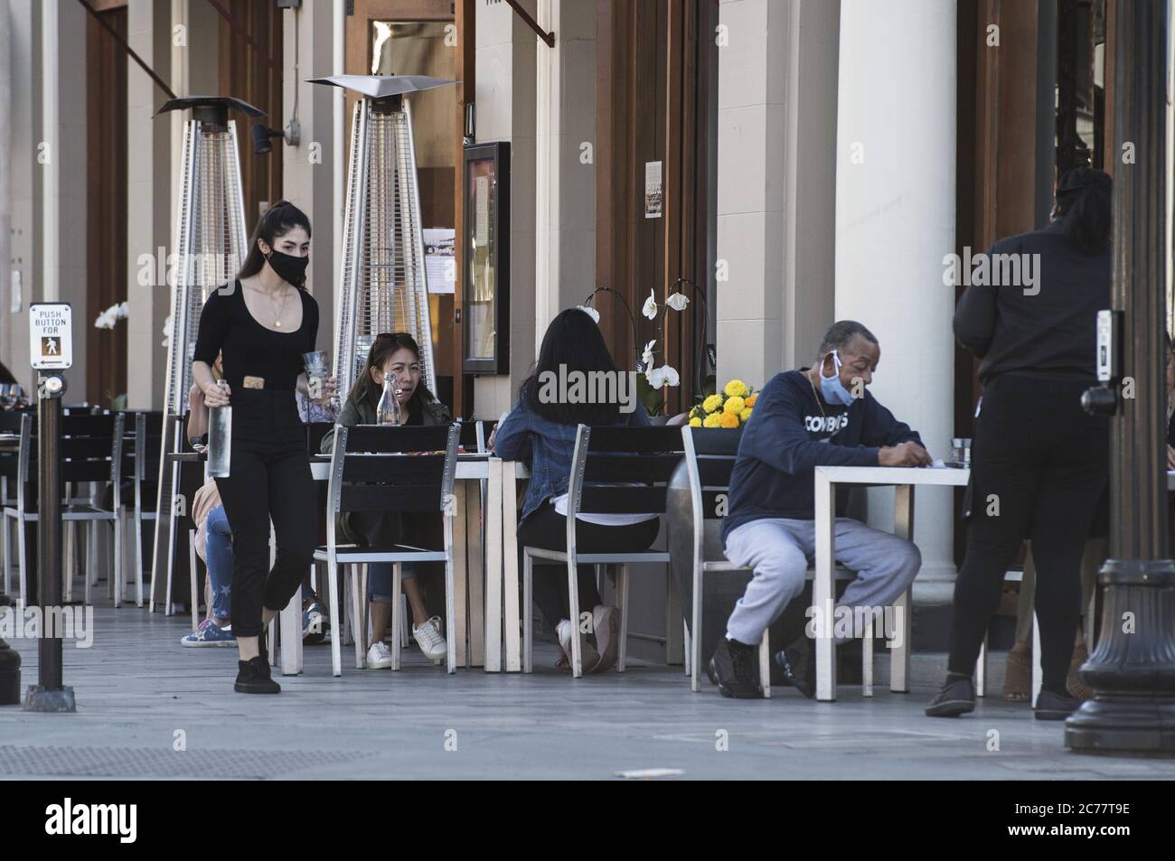 Burlingame, United States. 15th July, 2020. A waitress brings water to patrons seated on the sidewalk outside of Flights Restaurant in Burlingame, California on Tuesday, July 14, 2020. California's Governor Gavin Newsom has ordered a rollback in openings in some counties amid a spike in COVID-19 cases across the state. Photo by Terry Schmitt/UPI Credit: UPI/Alamy Live News Stock Photo