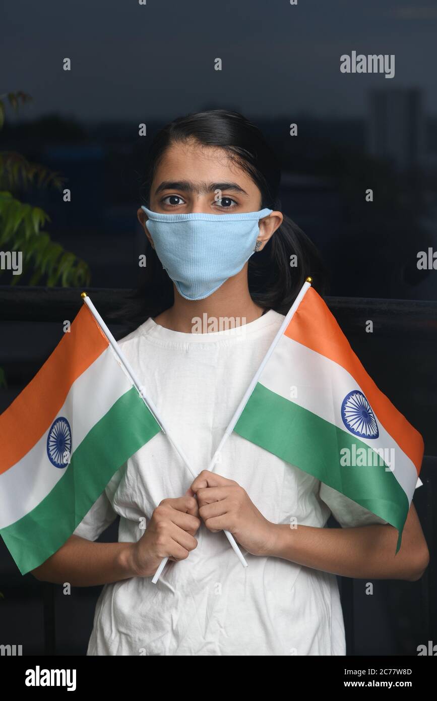 Kerala, India. July 13, 2020.Corona virus pandemic or COVID-19 in India. Young girl holding Indian flag wearing safety mask. Stock Photo
