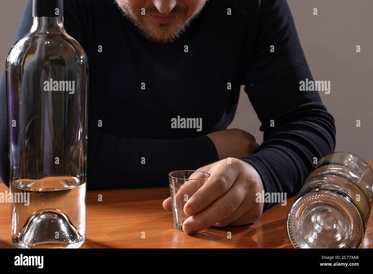 A man in alcoholic intoxication holds a glass of alcohol. Alcoholism, addiction, delirium Stock Photo