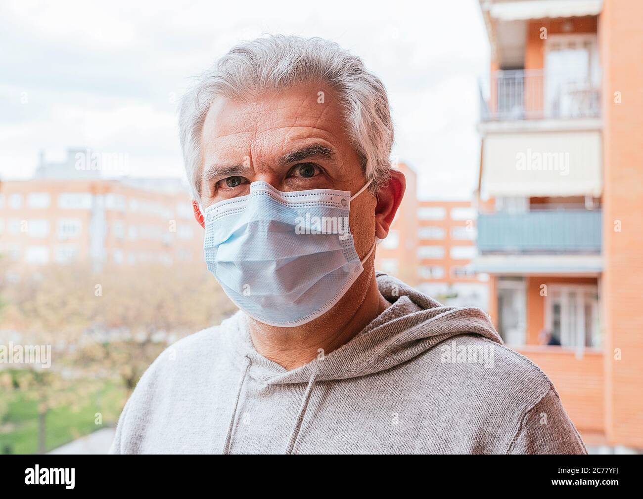 Older white-haired man wearing a mask against Coronavirus, Covid - 19 or any other disease, in the street Stock Photo