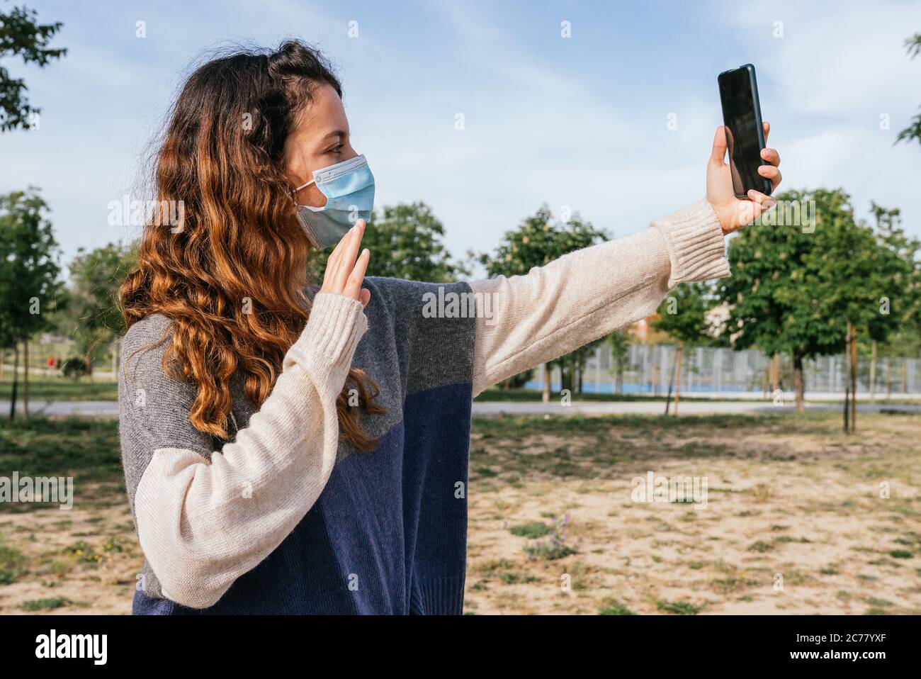 Social distancing. Teenager in a park talking to her family on the phone. Respecting social distance. Pandemic. Coronavirus devices. Coronavirus. Covi Stock Photo