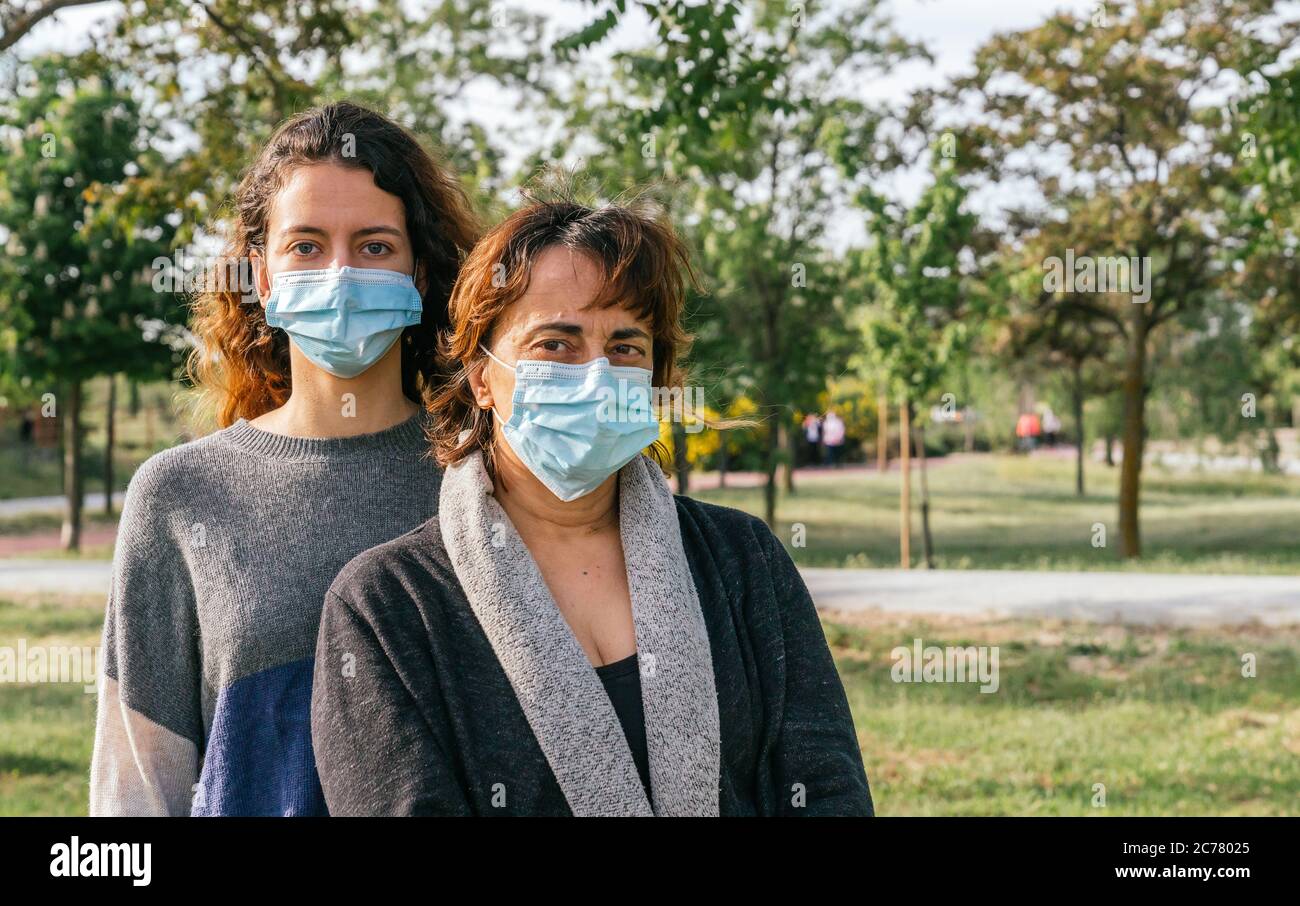 Social distance. Mother and daughter with a protective mask, hugging in a park. Ending the Coronavirus Pandemic. Coronavirus devices. Social distancin Stock Photo