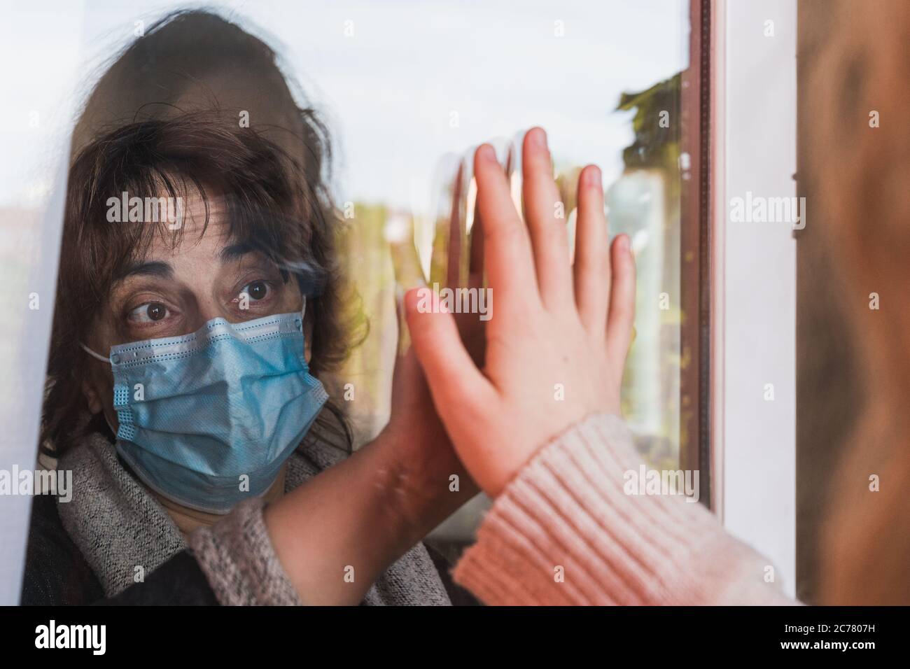 Social distancing among the family, Mother and daughter on a window plane. Coronavirus. Covid-19. Pandemic. Coronavirus devices Stock Photo