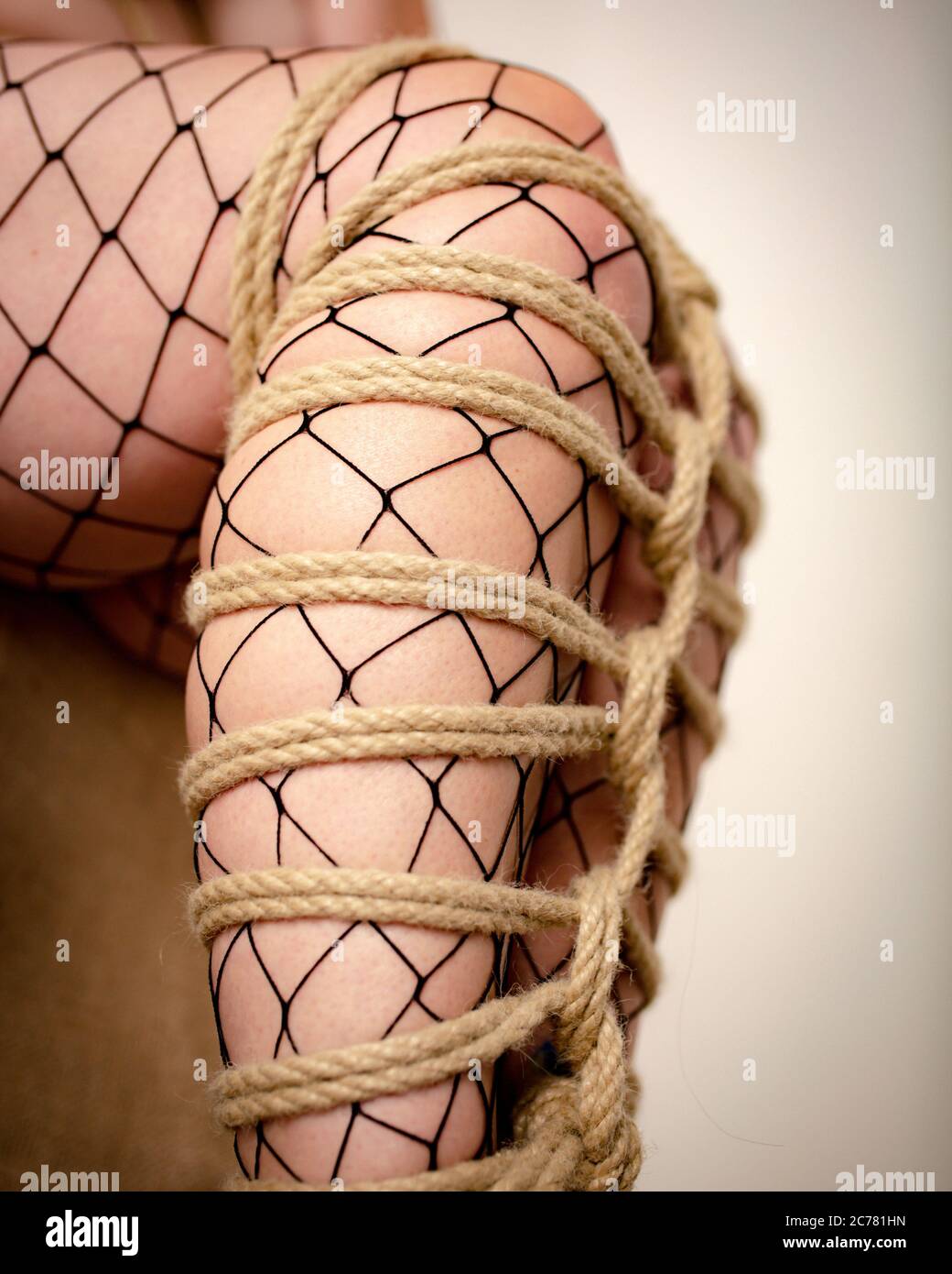 Close-up stocking legs of young woman tied into futomomo with hemp rope. Ancient Japanese art of shibari Stock Photo