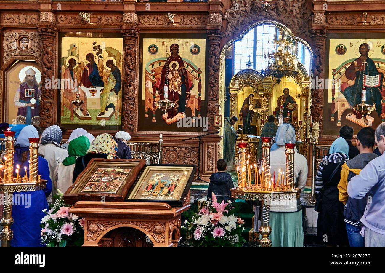Astrakhan, Russia.  The Dormition Cathedral is located in the Kremlin of Astrakhan. The crowd of believers gathers in front of the iconostasis covered with icons. The iconostasis is considered as a door to the divine world. Stock Photo