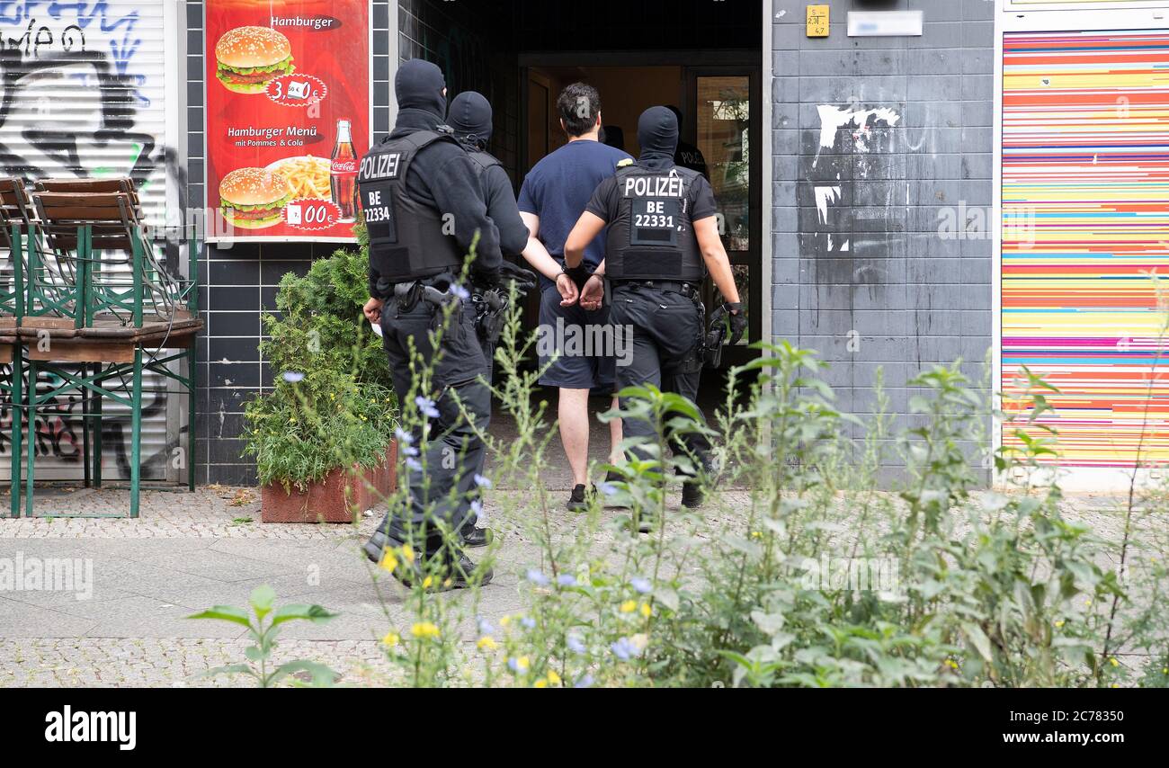 Berlin, Germany. 15th July, 2020. Police officers lead a handcuffed man into a house in Berlin-Kreuzberg as part of a large-scale raid on suspects from the Islamist scene in various parts of Berlin. Round 450 officers are on duty. Credit: Paul Zinken/dpa - ATTENTION: Sign on the house wall pixelated for legal reasons/dpa/Alamy Live News Stock Photo