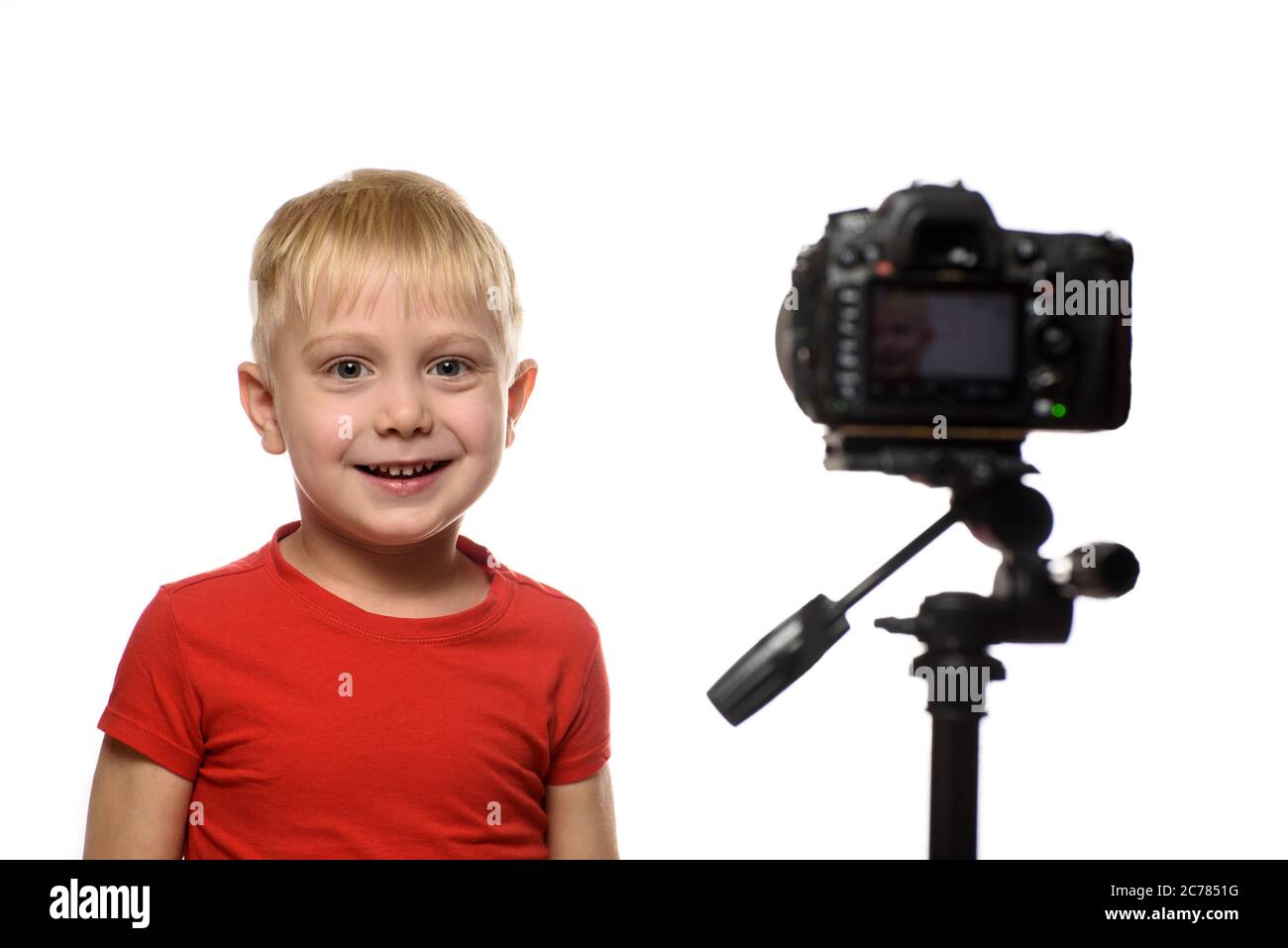 Smiling blond boy in front of the camera lens. Little video blogger. White background Stock Photo