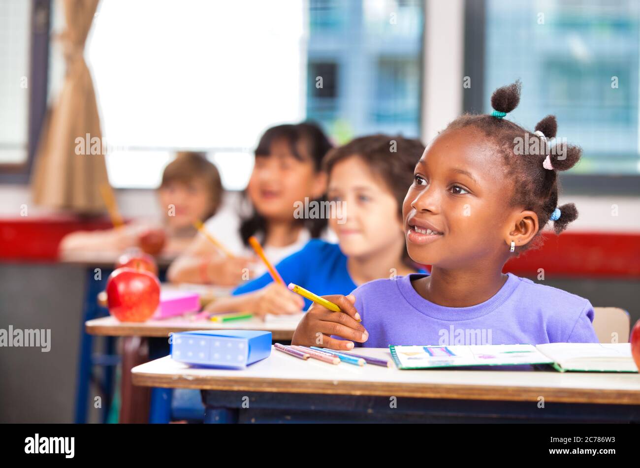 Elementary school scene. African schoolgirl with multi ethnic classmates in the classroom floowing teacher lesson Stock Photo