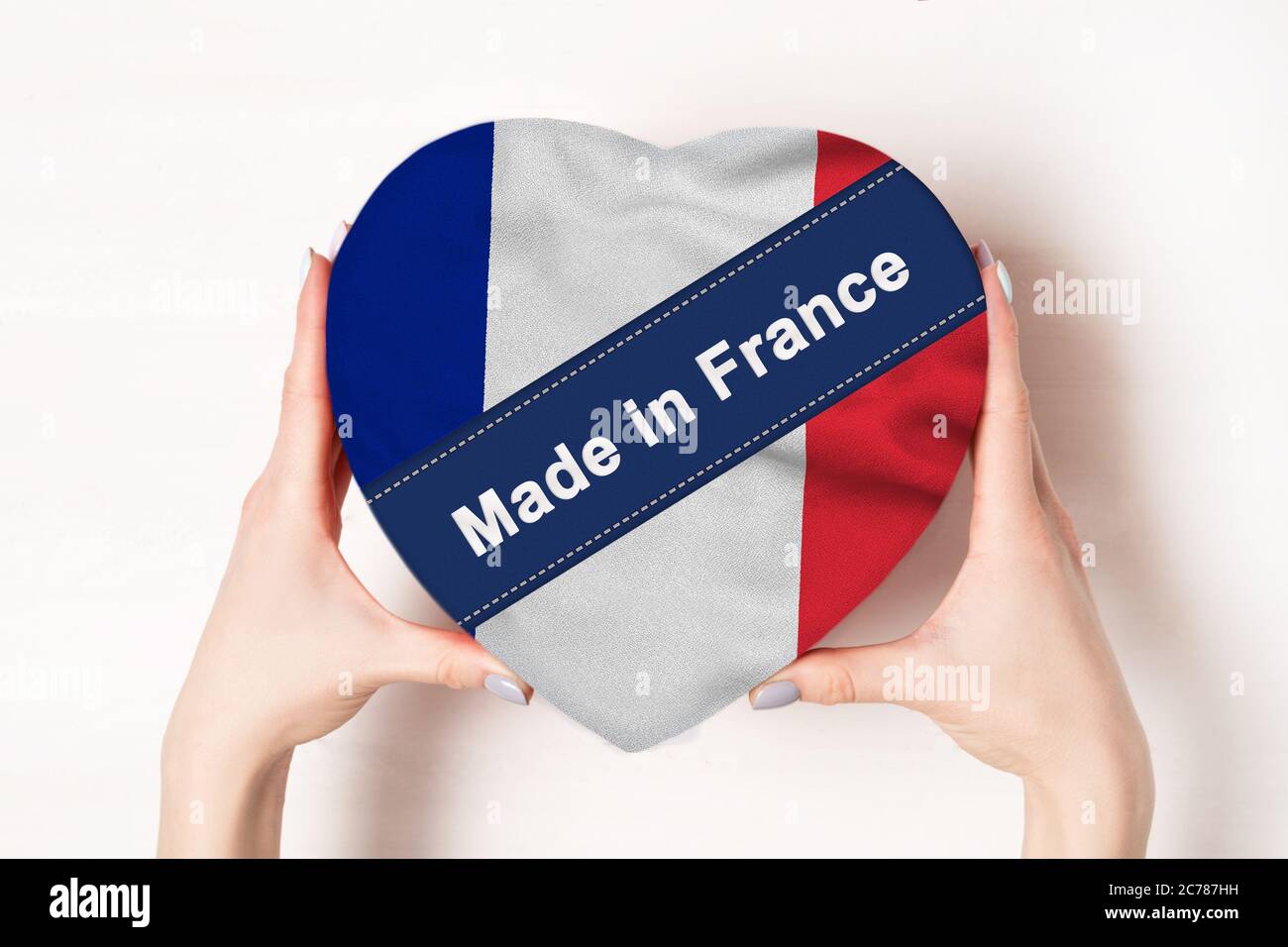 Inscription Made in France, the flag of France. Female hands holding a heart shaped box. White background. Place for text Stock Photo