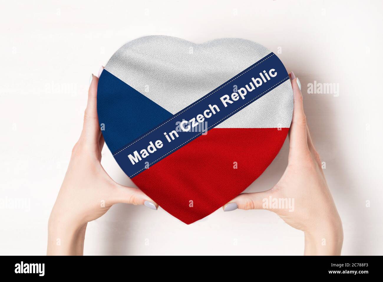 Inscription Made in Czech Republic, the flag of Czech Republic. Female hands holding a heart shaped box. White background. Stock Photo