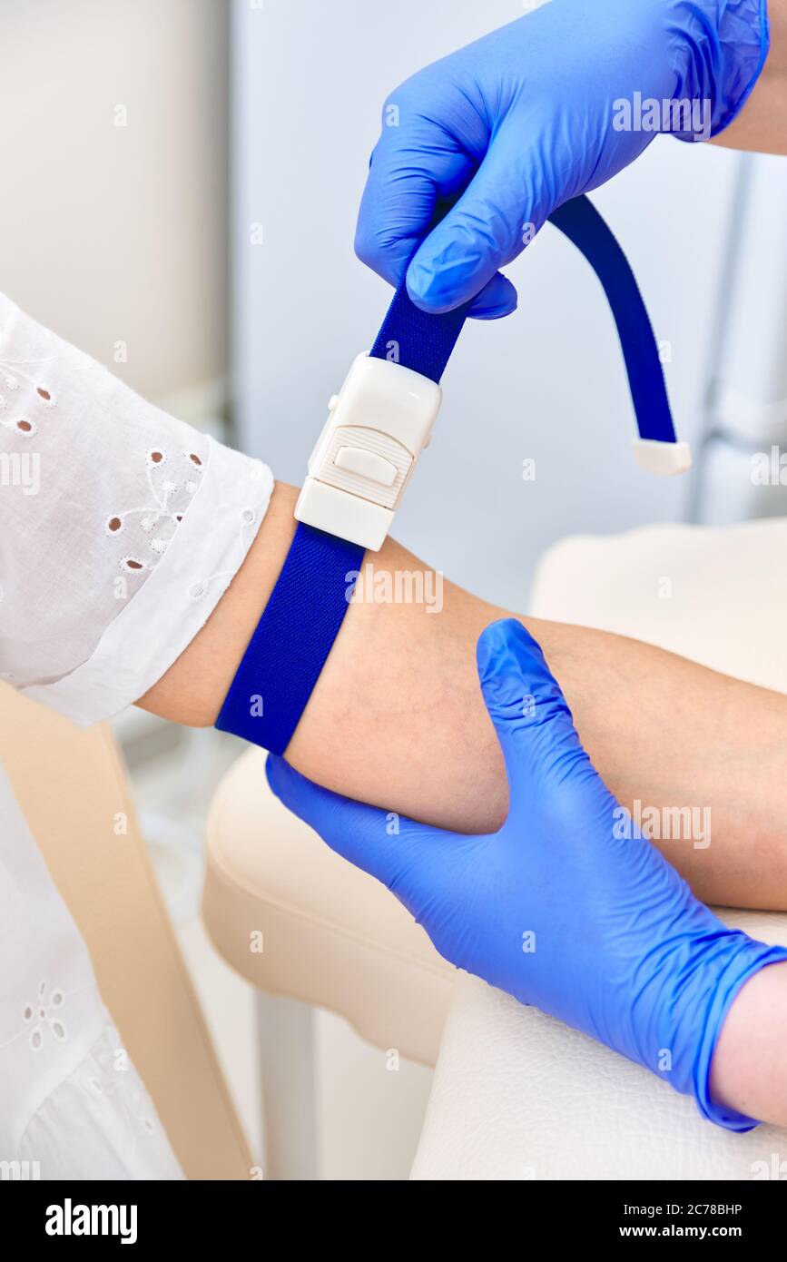 girl gives blood. doctor put a medical tourniquet on his arm Stock