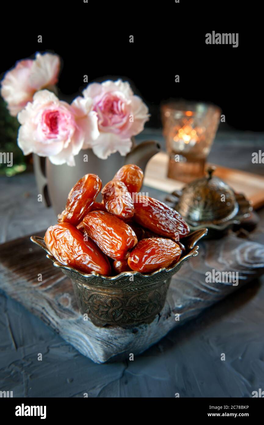 Sweet dried dates lie in a beautiful bowl on the table with candles ...