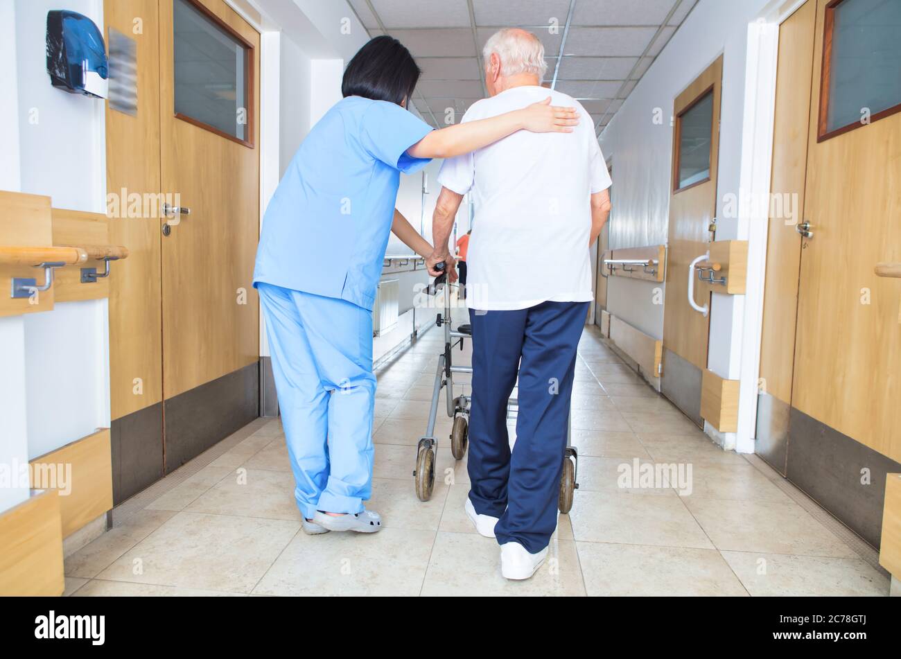 Asian nurse assisting elderly man with walker walking on the hospital ...