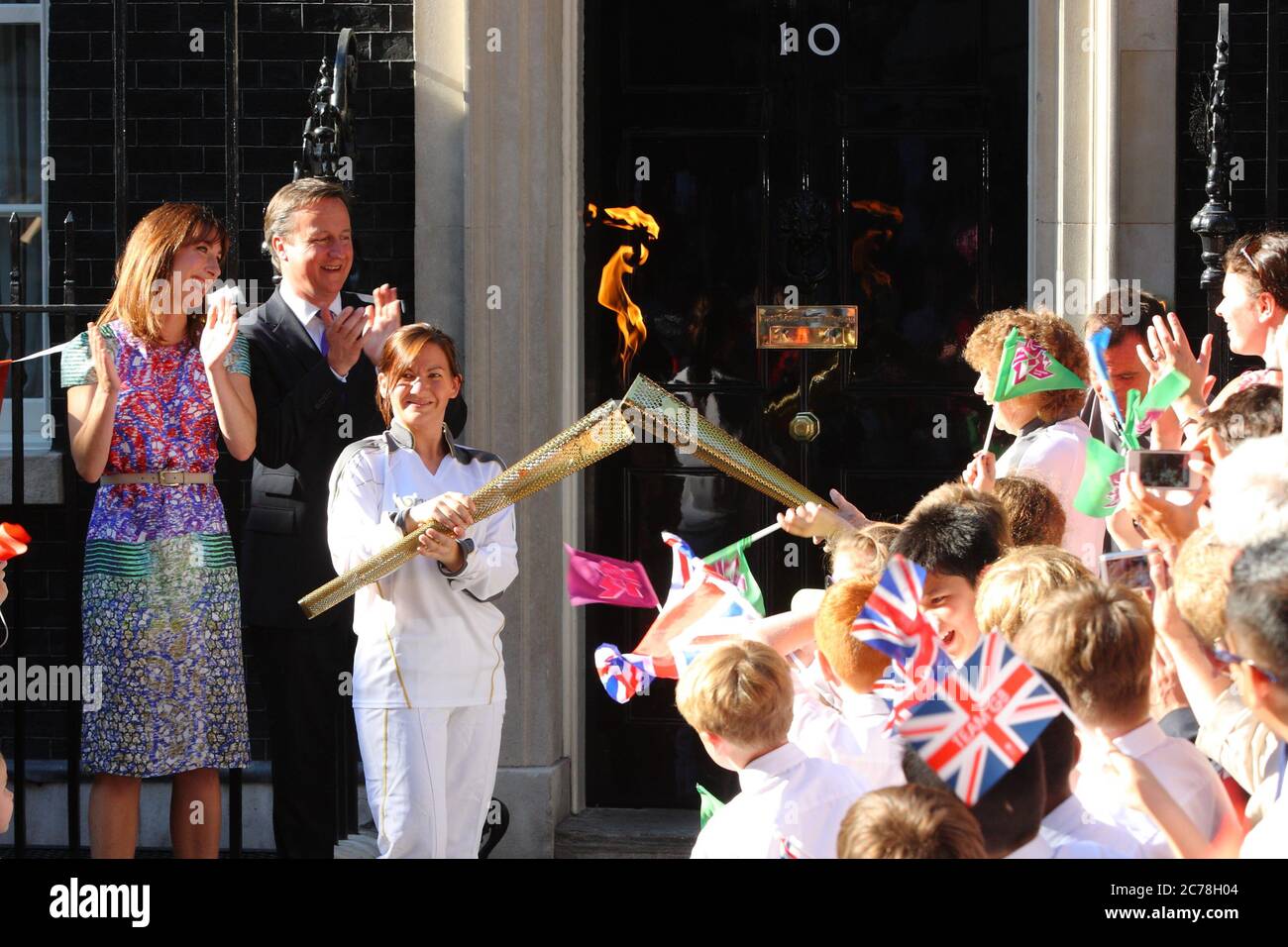 The Olympic Torch reaches Prime Minister David and Samantha Cameron at number 10 Downing Street carried by Ceri Davies who passed on the flame to Florence Rowe. 25 July 2012 --- Image by © Paul Cunningham Stock Photo