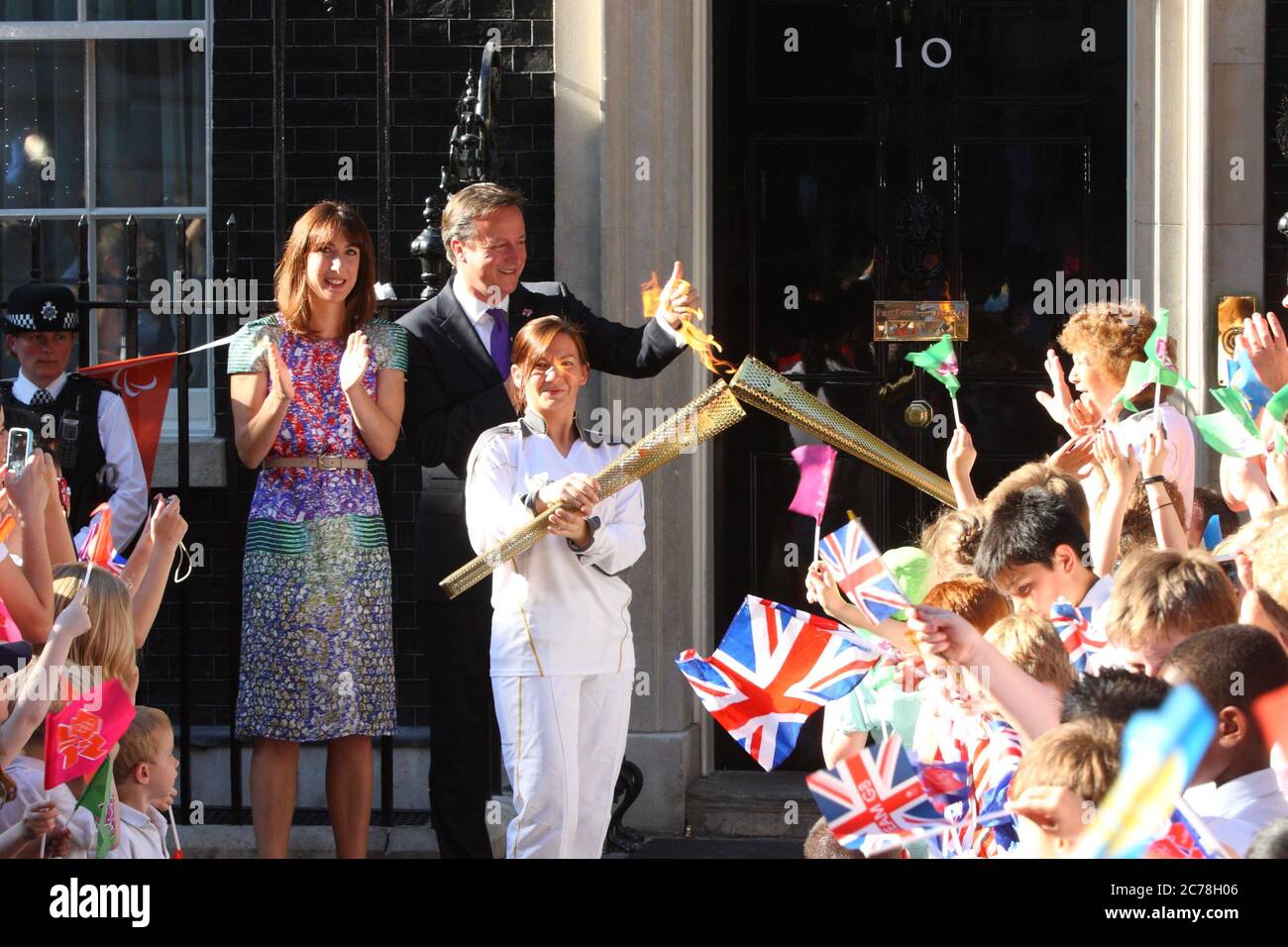 The Olympic Torch relay reaches Prime Minister David and Samantha Cameron at number 10 Downing Street carried by Ceri Davies who passed on the flame to Florence Rowe. 25 July 2012 --- Image by © Paul Cunningham Stock Photo