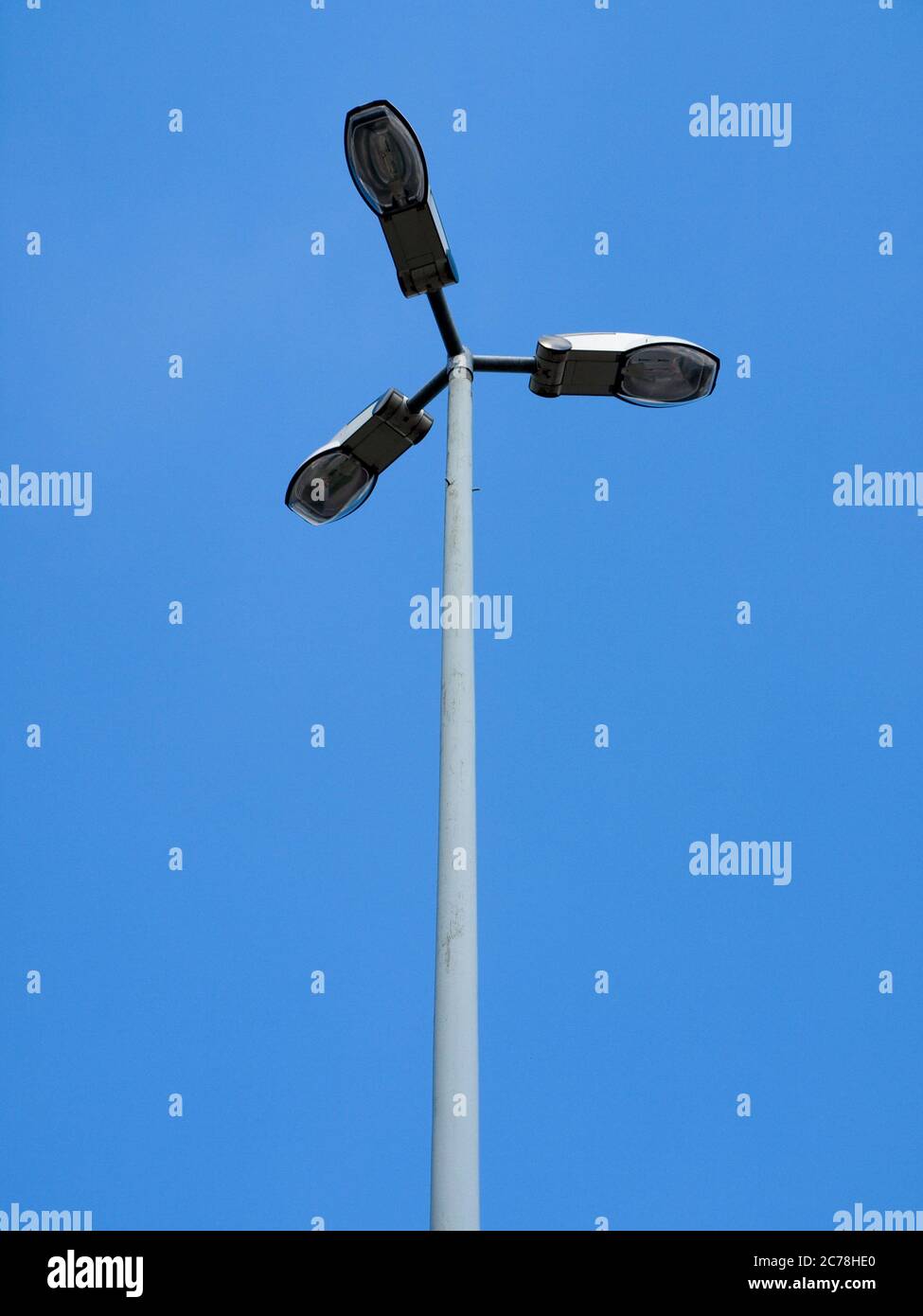 light post with three lamps in front of a blue sky. Stock Photo