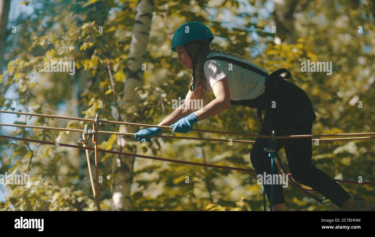 Woman Crossing Rope A woman in helmet crossing the rope bridge - an entertainment ...