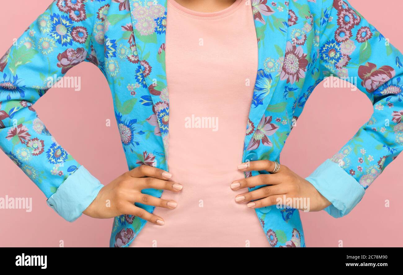 Fashion detail of a tailored floral blue jacket on a slender young woman standing with hand on hips in a close up on her midriff Stock Photo