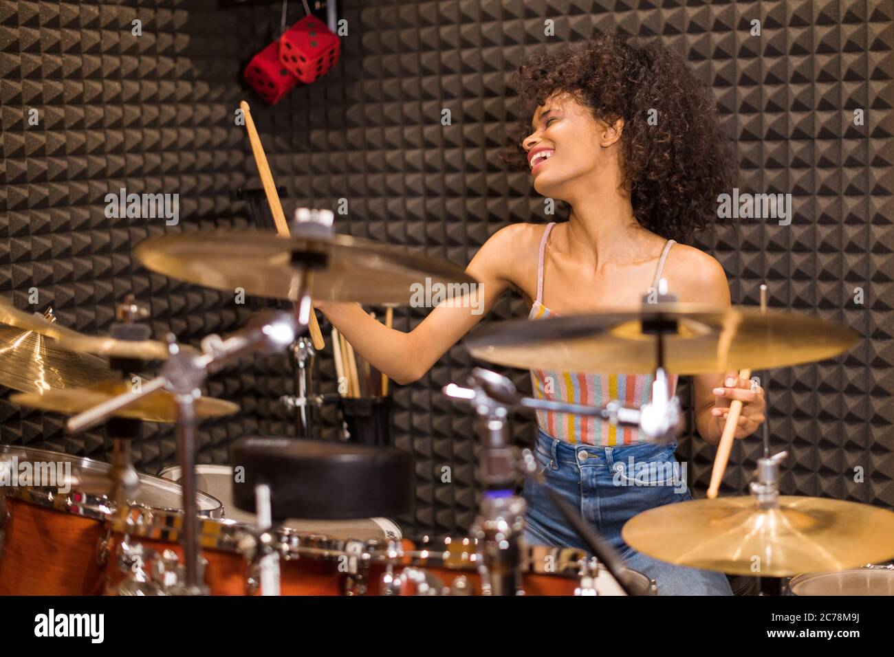 Young black female drummer in a recording studio immersed in the Young black female drummer in a recording studio immersed in the