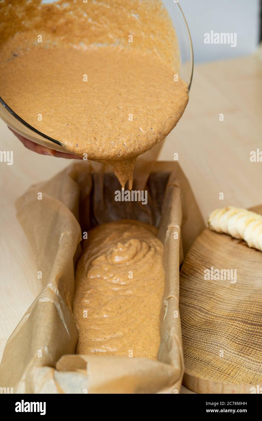 Easy to make dough for healthy, home made banana bread - putting from bowl to tray. Stock Photo