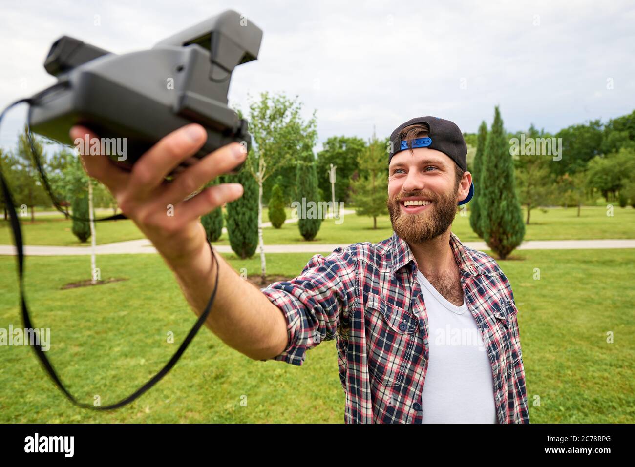 Young man with a retro camera in the park. Stock Photo
