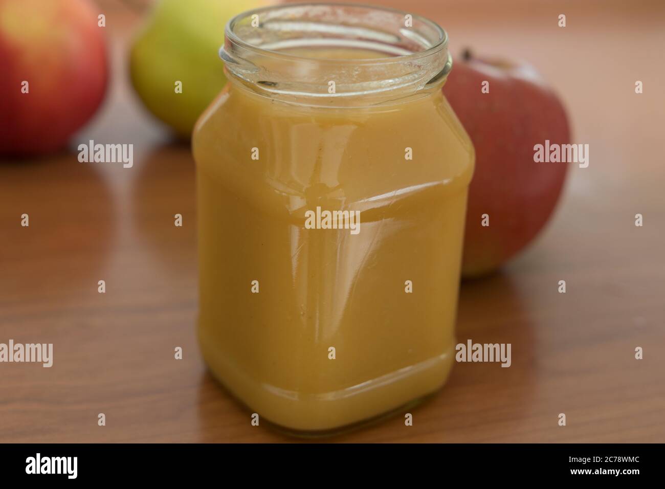 closeup of a glass filled with apple puree and fresh apple in the background Stock Photo
