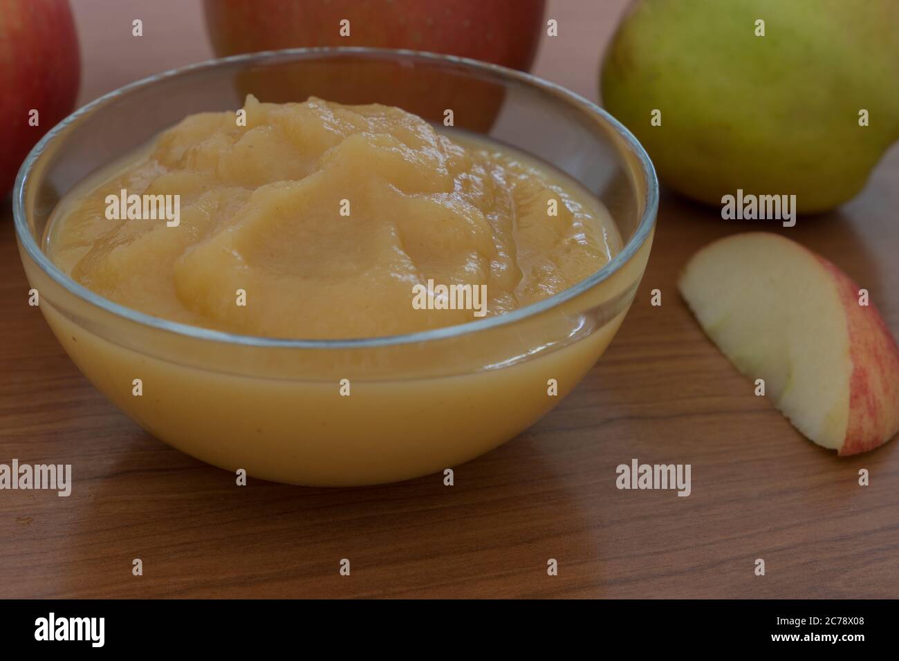 closeup of a glass bowl filled with apple puree and fresh apple in the background Stock Photo